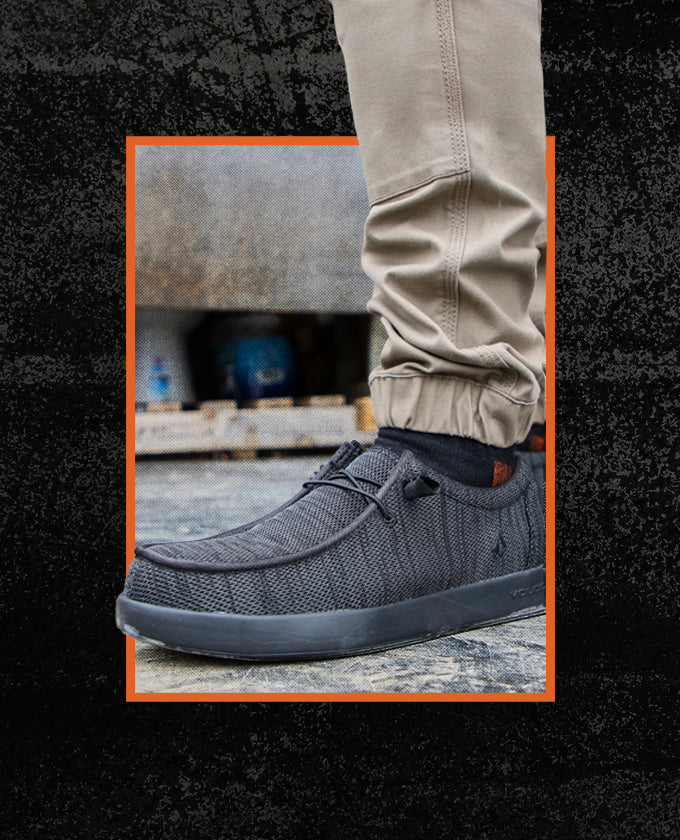 Gray casual shoe worn with beige pants on a textured surface