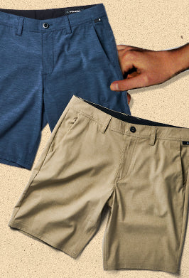 Flat lay of shorts with a hand holding one pair