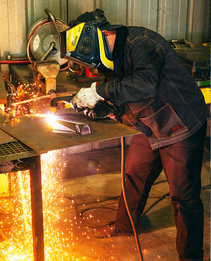 Person welding metal with sparks flying in a workshop setting