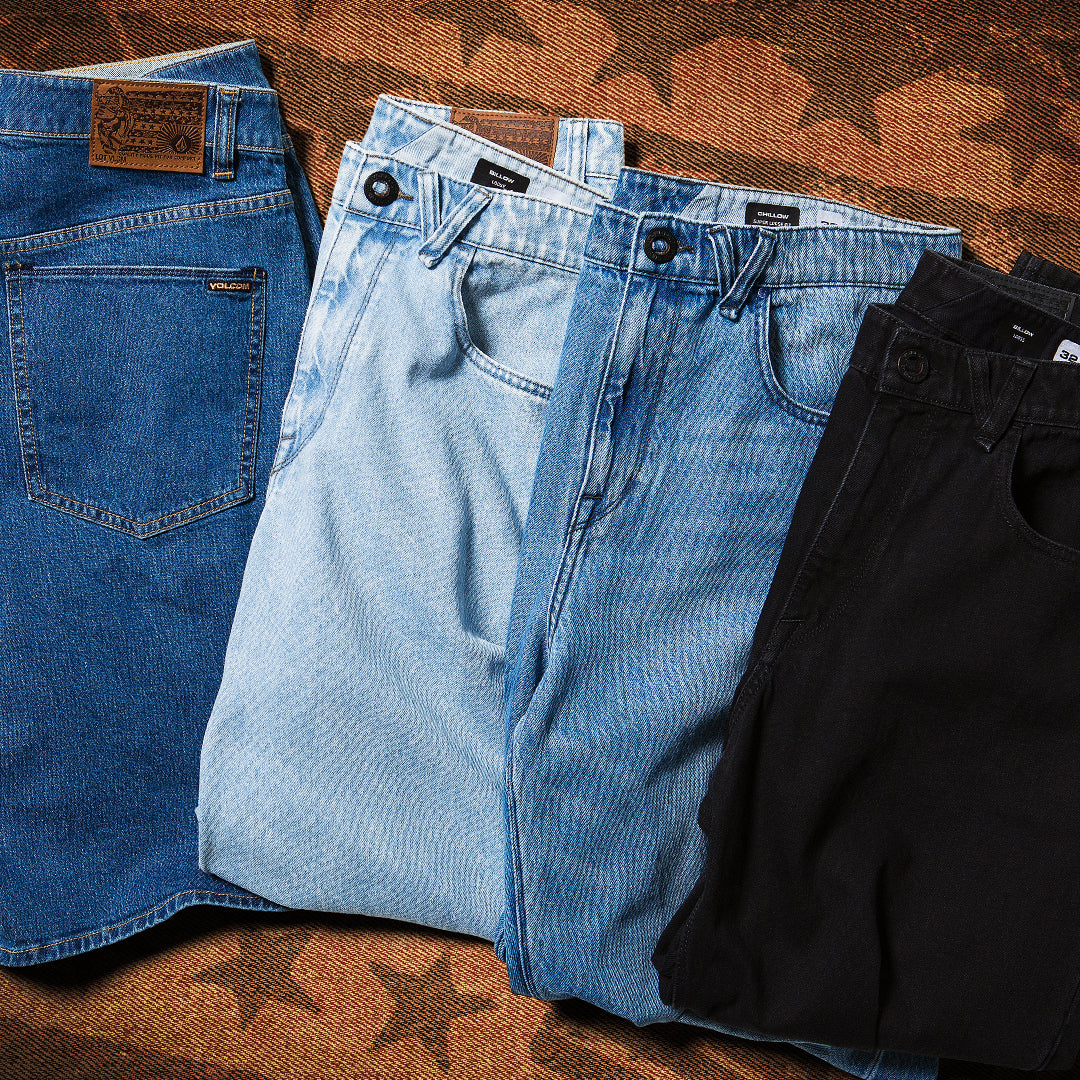 Three pairs of jeans in blue and black on a wooden surface