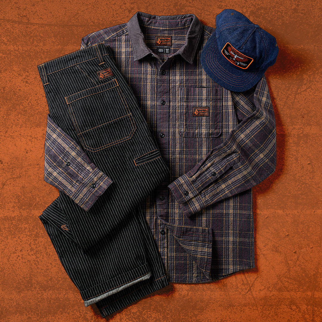 Plaid shirt, jeans, and cap on a textured brown surface