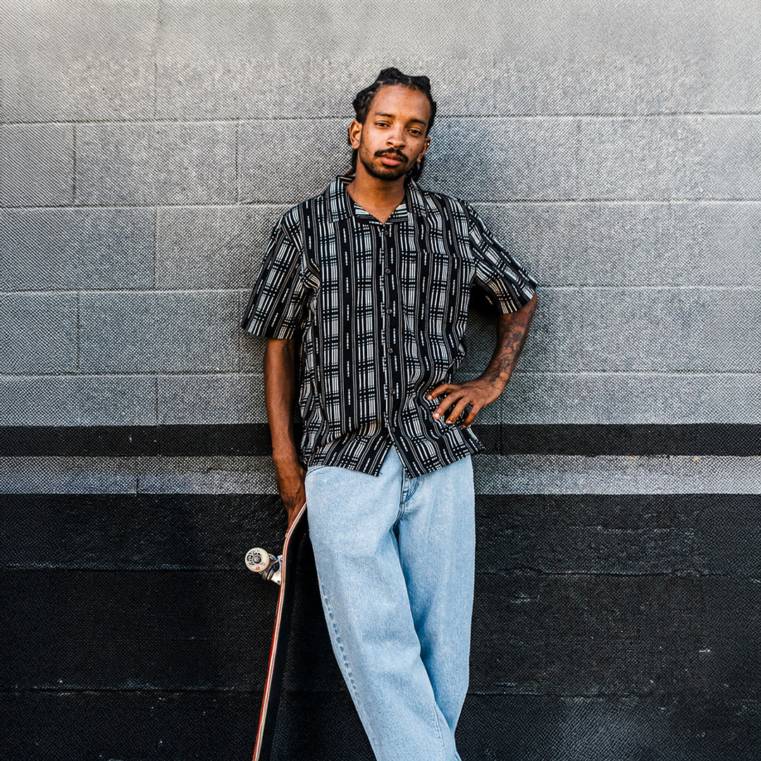 Man leaning against a textured wall with a skateboard