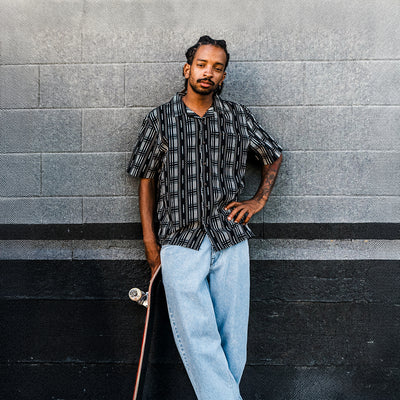 Man leaning against a textured wall with a skateboard