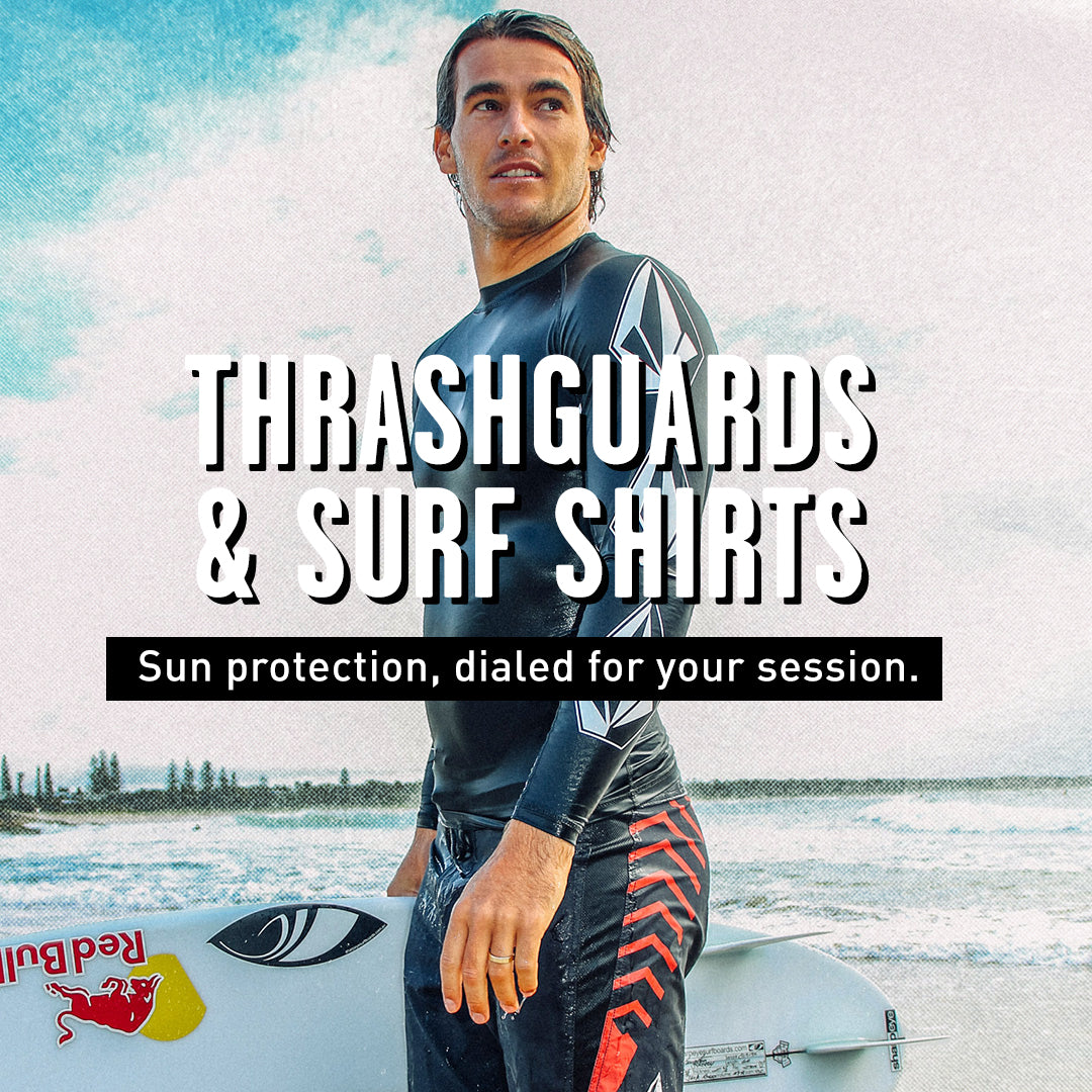 Man in a wetsuit standing on a surfboard with text about 'Thrashguards & Surf Shirts' and sun protection.