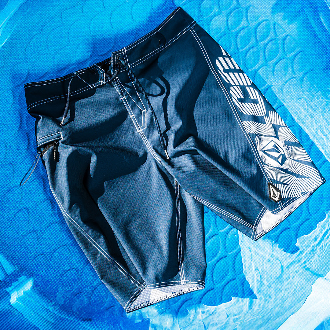 Blue swim shorts with branding on a blue textured surface