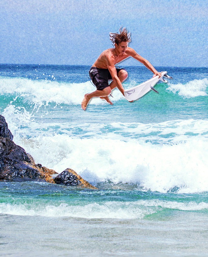 Person surfing on a wave with a blue sky and ocean background