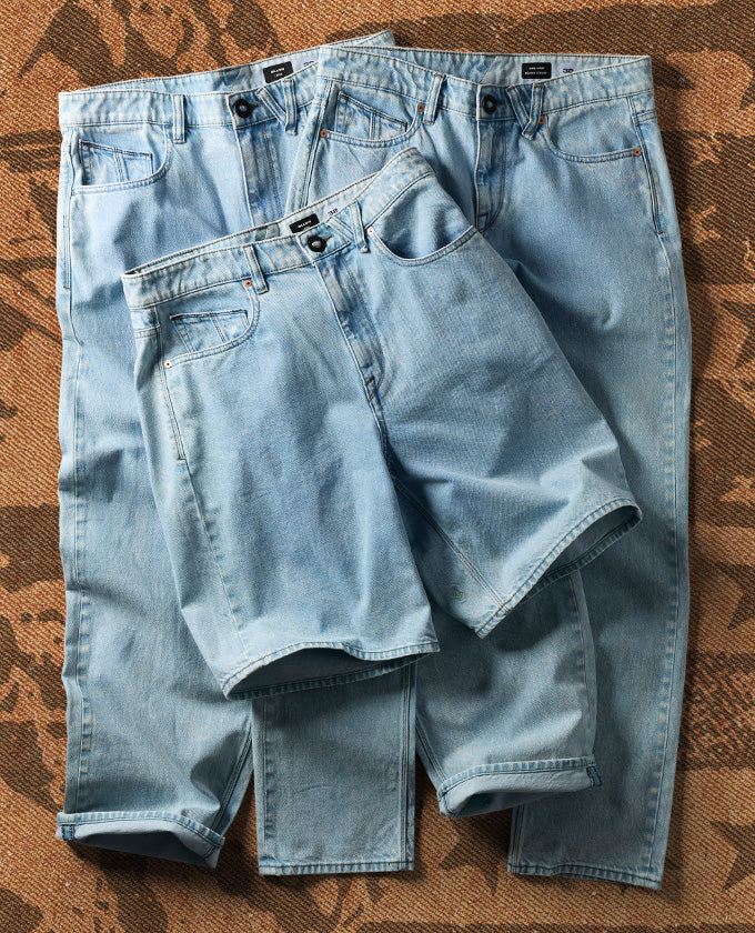 Blue denim shorts placed on top of pants on a brown patterned floor