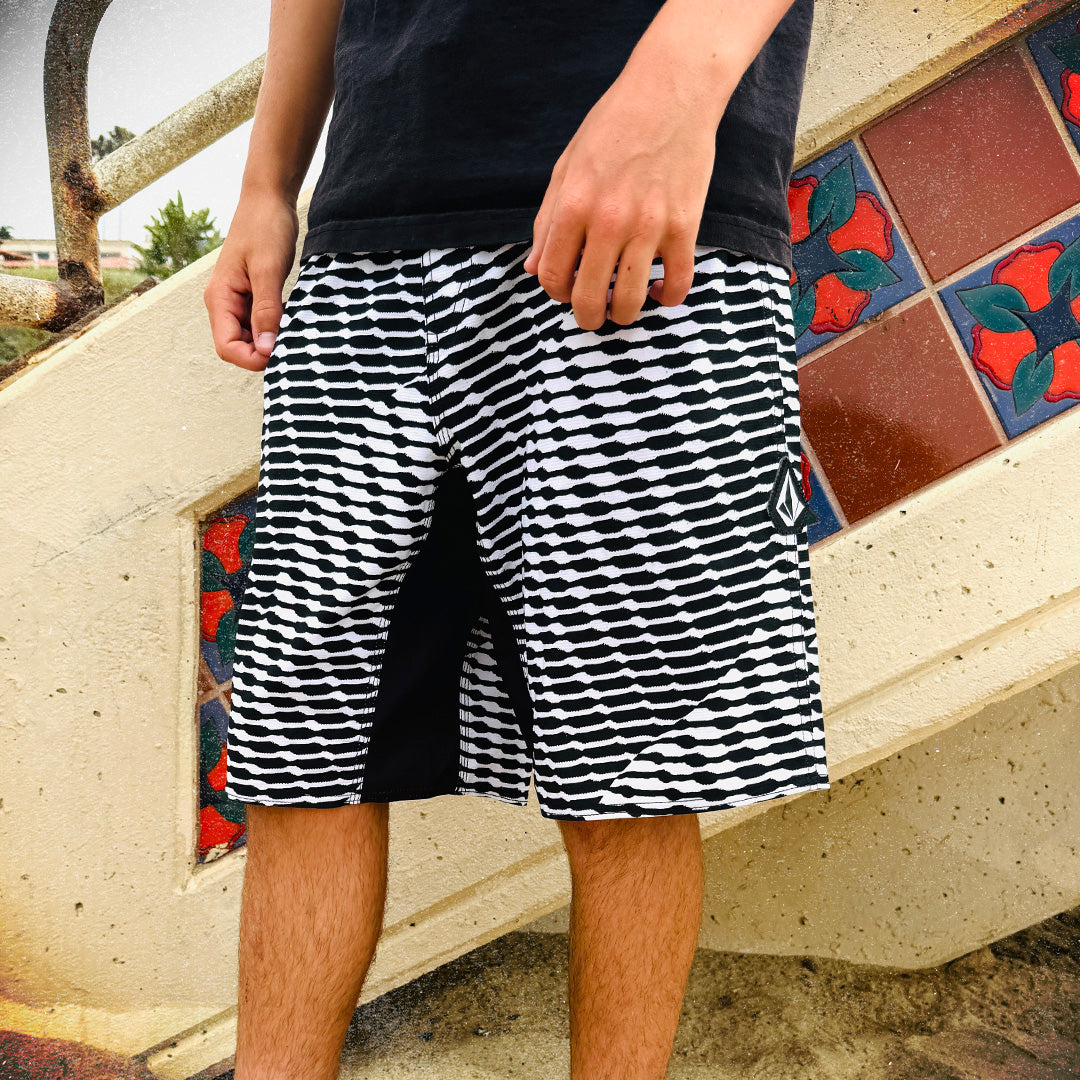 Person wearing black and white striped shorts standing on a tiled step.