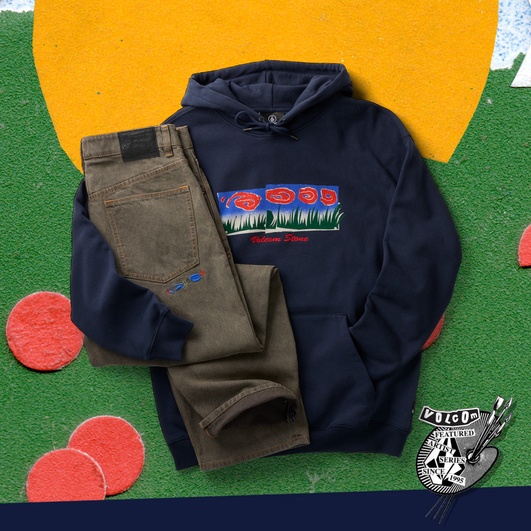 A navy blue hoodie with a colorful graphic print on the chest, styled flat-lay with olive green pants on a colorful felt background. A 'Polo Collection' logo badge is visible in the bottom right corner.