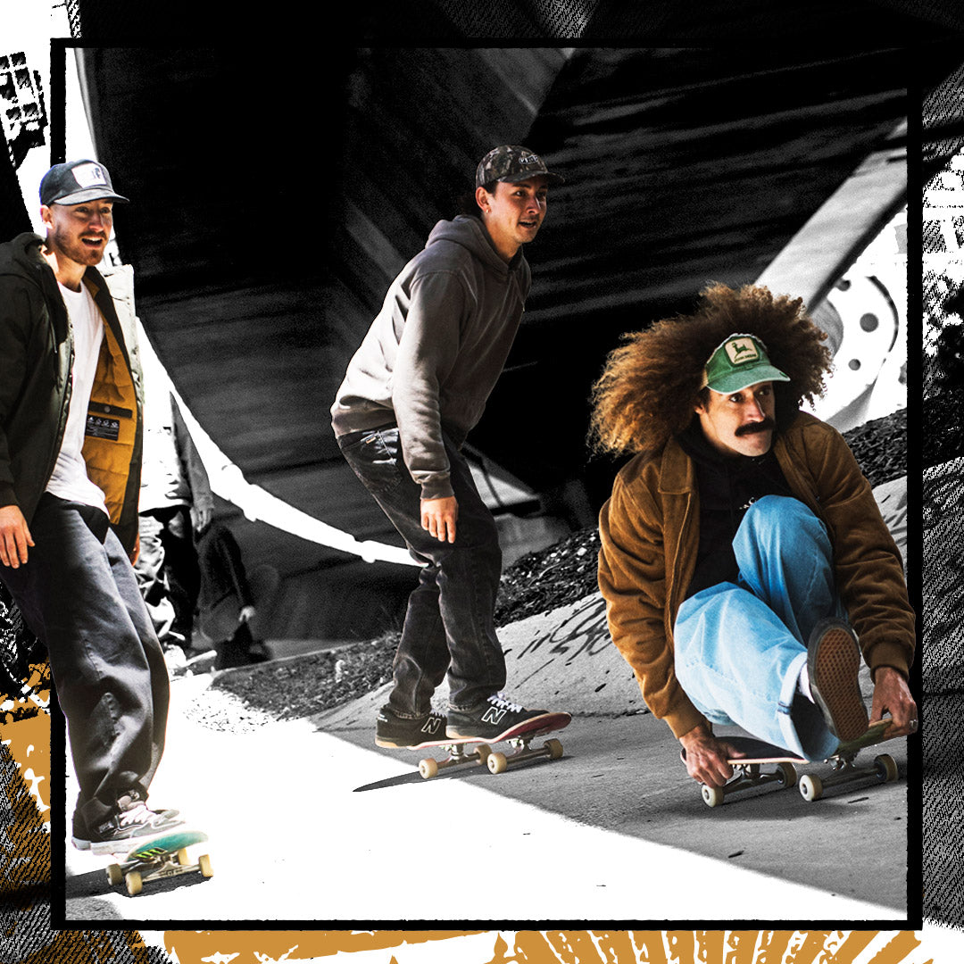 Three men skateboarding in an outdoor urban setting with a black-and-white tunnel background and a tan graphic border overlay.