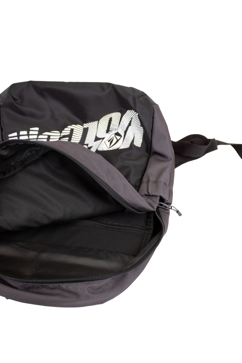 A black Volcom Men's Summer School backpack with a partially open zipper reveals its empty interior. This lightweight backpack features bold white graphic text on the front and includes a convenient laptop sleeve for easy organization.