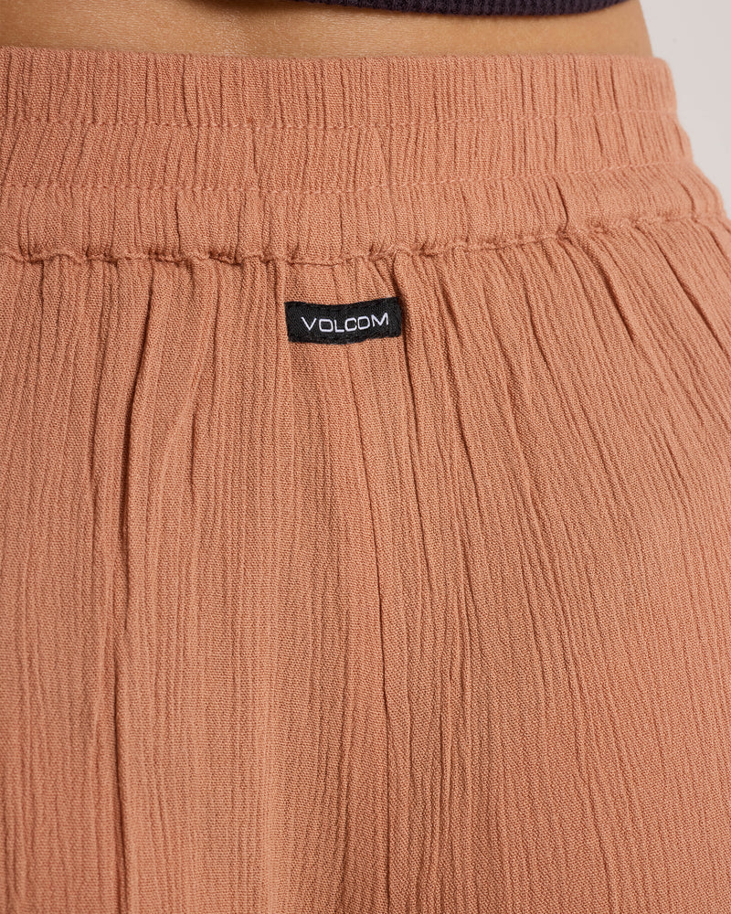 Close-up of Volcom Women’s Stoneshine Junki Pants in a relaxed, rust-colored wide-leg style featuring an elastic waistband and a small black label.