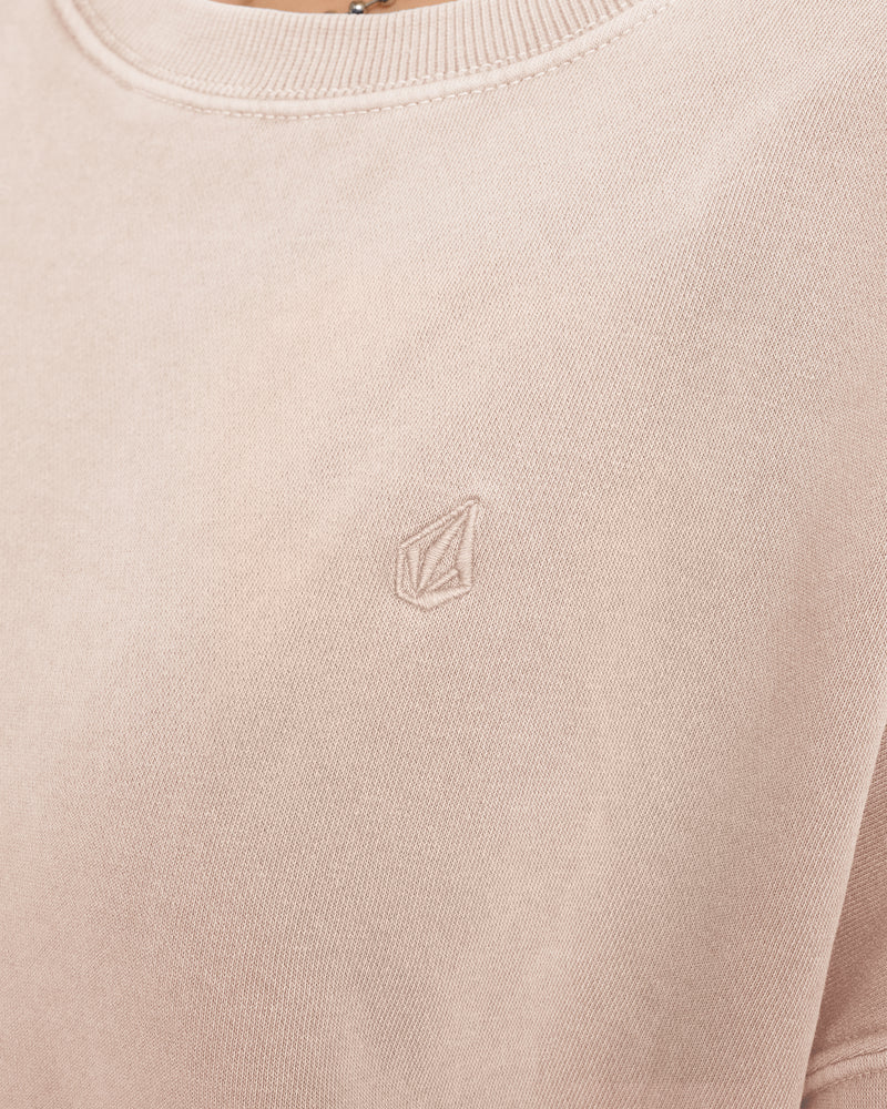 A close-up of the Volcom Women’s Stone Soft Crew shows a light beige sweatshirt made from cozy slub brushed back fleece, featuring a small, minimalist geometric logo embroidered on the left chest.
