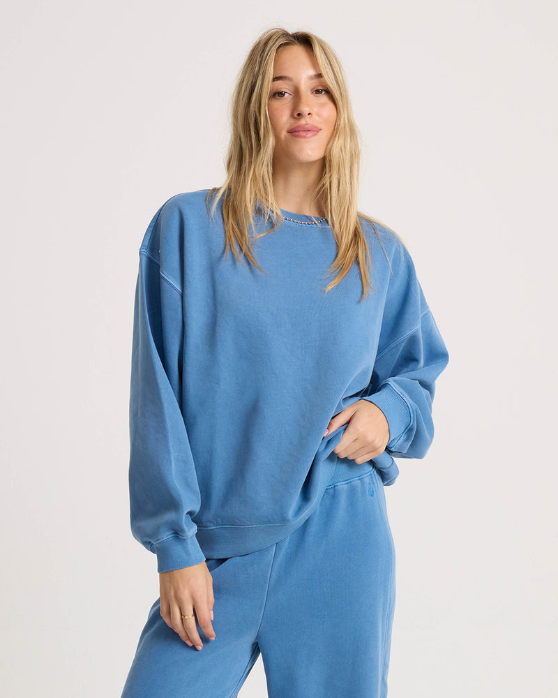 A woman wearing a relaxed dropped-shoulder Women’s Stone Soft Crew sweatshirt and matching sweatpants.