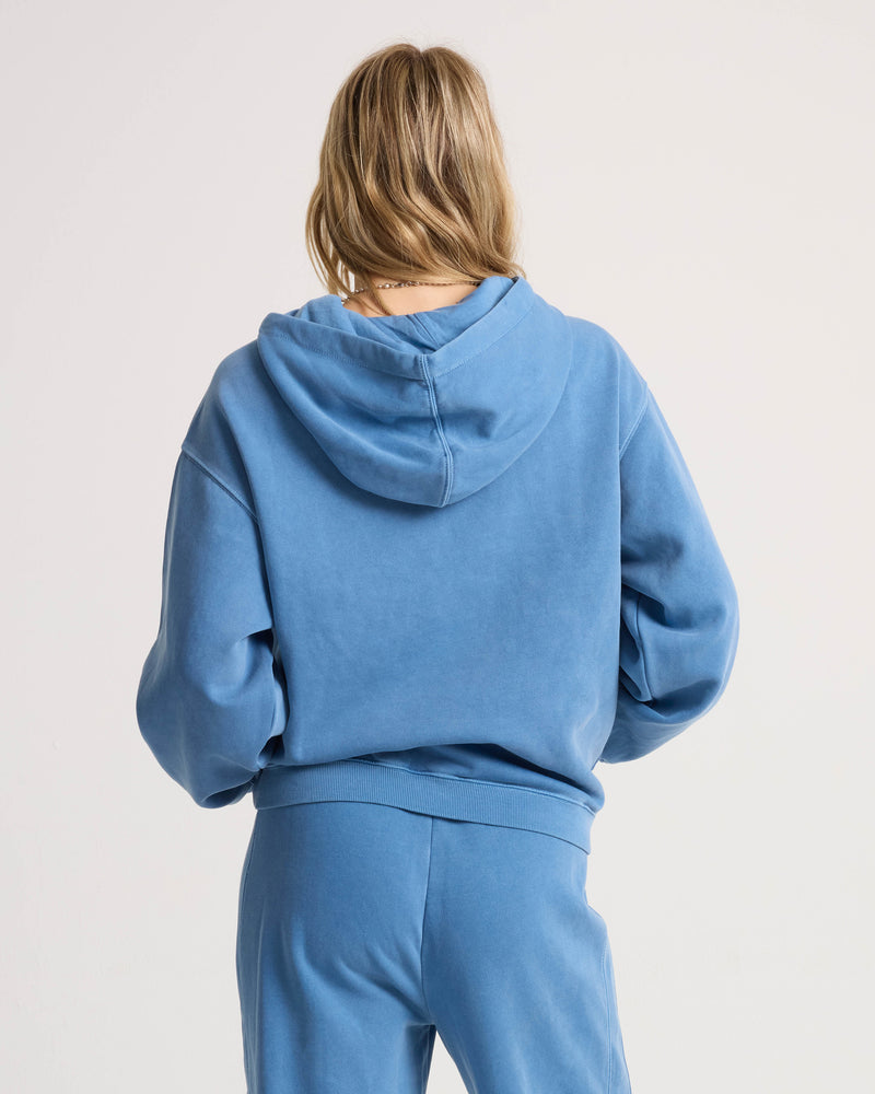 Back view of a person wearing a relaxed fit blue Women’s Stone Soft Hoodie and matching pants.