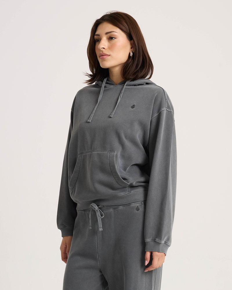 A person wearing a relaxed vintage black Volcom Women’s Stone Soft Hoodie with a front kangaroo pocket and a small logo on the chest.