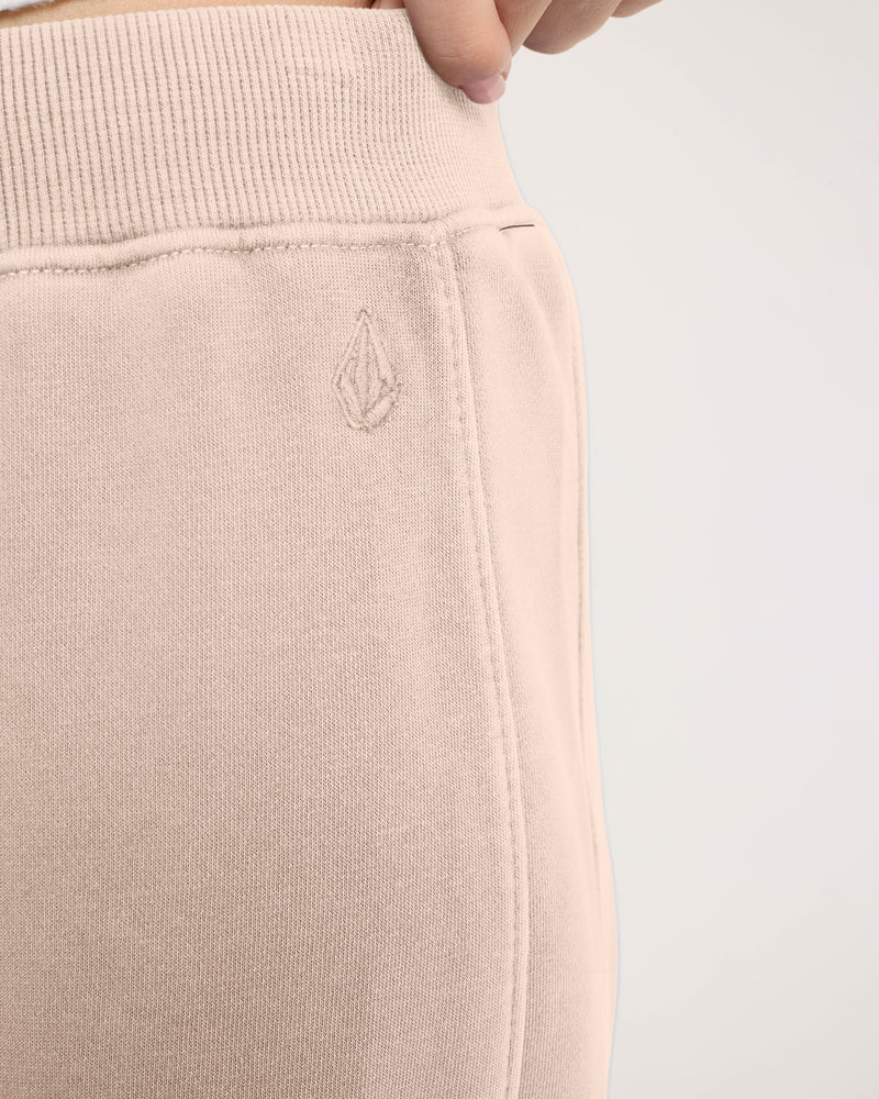 Close-up of Volcom Women’s Stone Soft Pant, featuring loose-fit, khaki-colored fleece with an elastic waistband and a small embroidered stone logo on the hip.