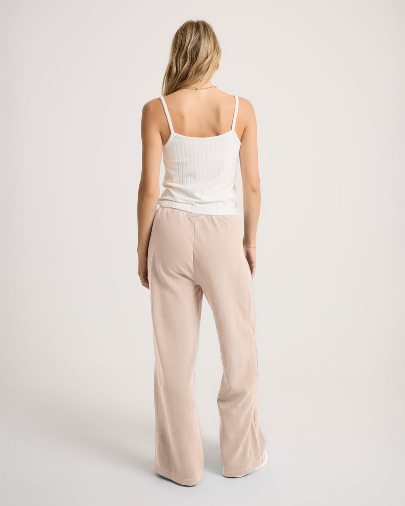 A person seen from behind wears a white ribbed tank top and Women’s Stone Soft Pant in loose-fit, light tan fleece.