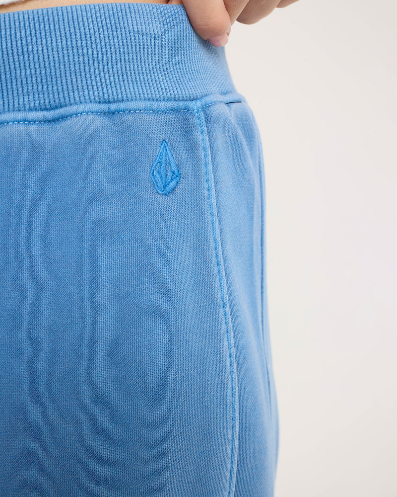 Close-up of bright blue Volcom Women’s Stone Soft Pant featuring a tie-front, ribbed waistband, and a small embroidered diamond-shaped logo on the hip.