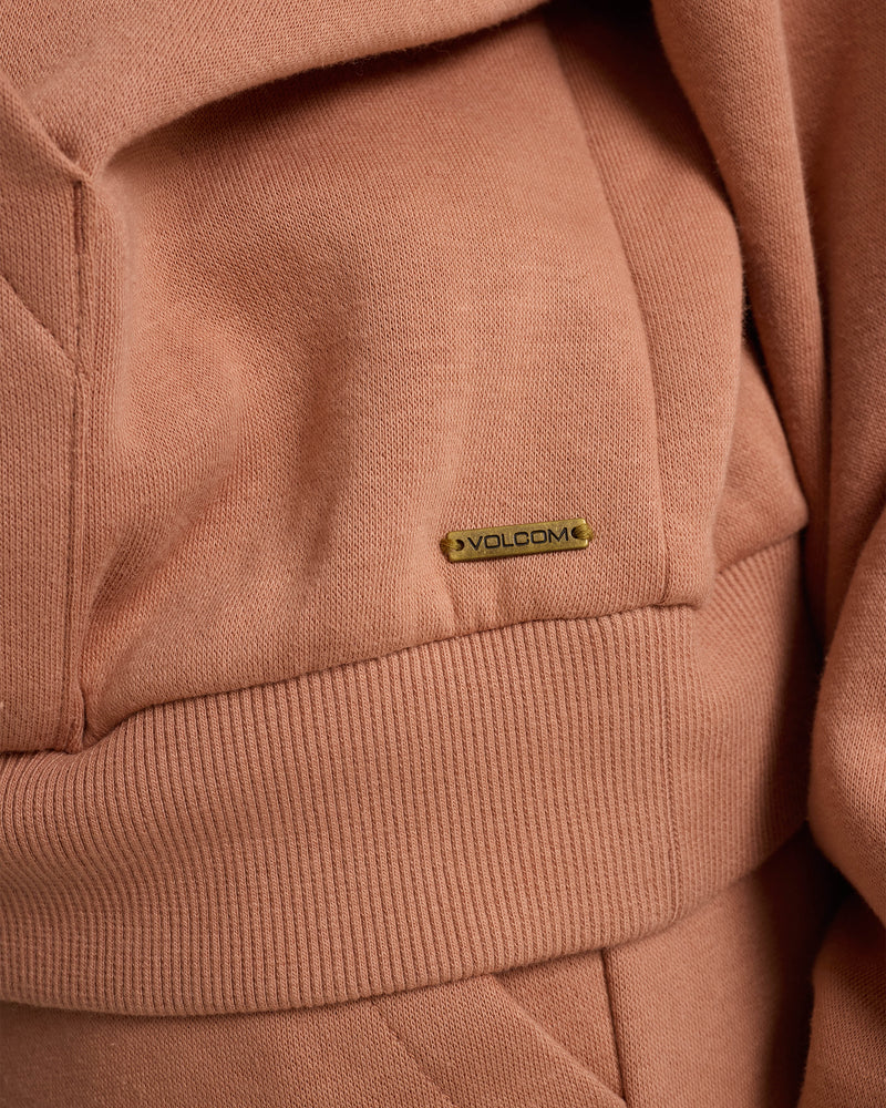 Close-up of a soft, peach-colored fabric with ribbed details and a gold Volcom tag—ideal for the Women’s In A Cinch Sweatshirt by Volcom in Mocha Mousse.