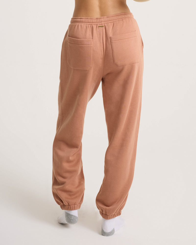 Someone wears Volcom Women’s In A Cinch Jogger Pant in light brown with an oversized fit and back pockets, standing in white socks on a light background for everyday comfort.