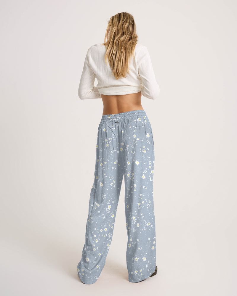 A person seen from behind wears a white long-sleeve crop top and Volcom Women’s Longboard Wide Leg Pant, which are lightweight viscose with a small white daisy print.