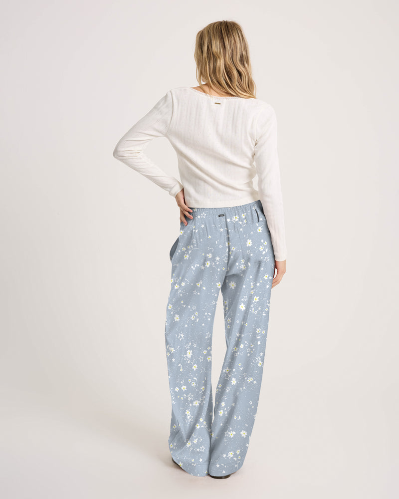 Woman from behind wearing a white long-sleeved top and Volcom Women’s Longboard Wide Leg Pant in a light blue floral print.