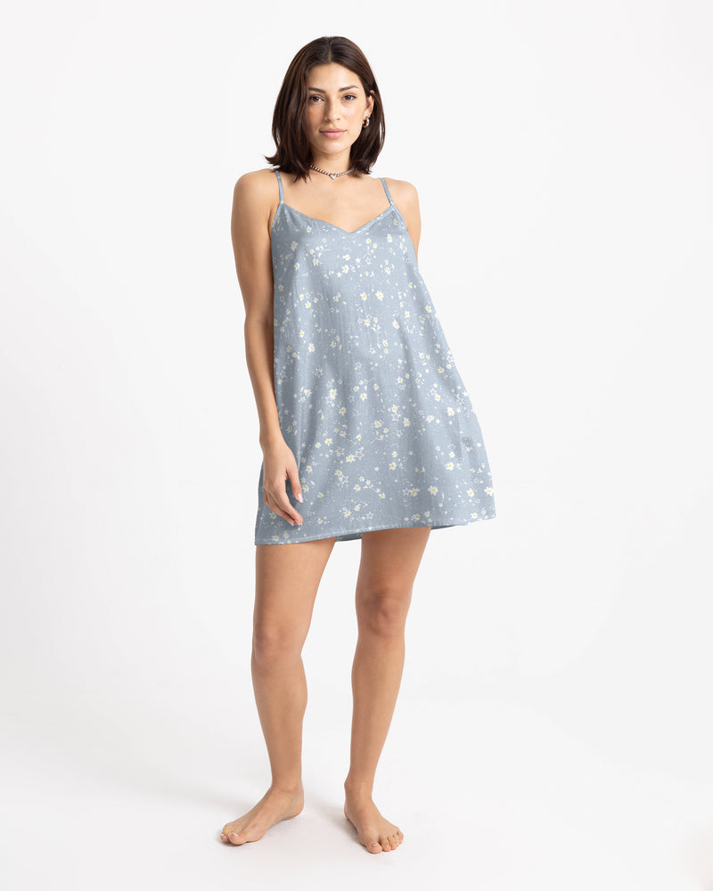 A person wears a light blue Volcom Women’s Boss Beach Mini Dress in a slip silhouette with a small white floral pattern.