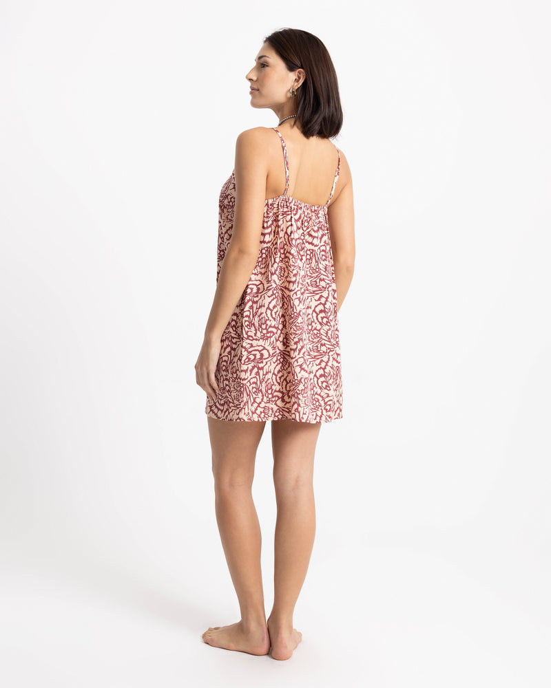A person wearing a Volcom Women’s Boss Beach Mini Dress, which features a red and white swirling print.