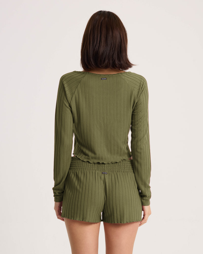 A person with shoulder-length dark hair wears a ribbed long-sleeve top and the Volcom Women’s Sun Lounge Short, shown from the back against a plain light background.
