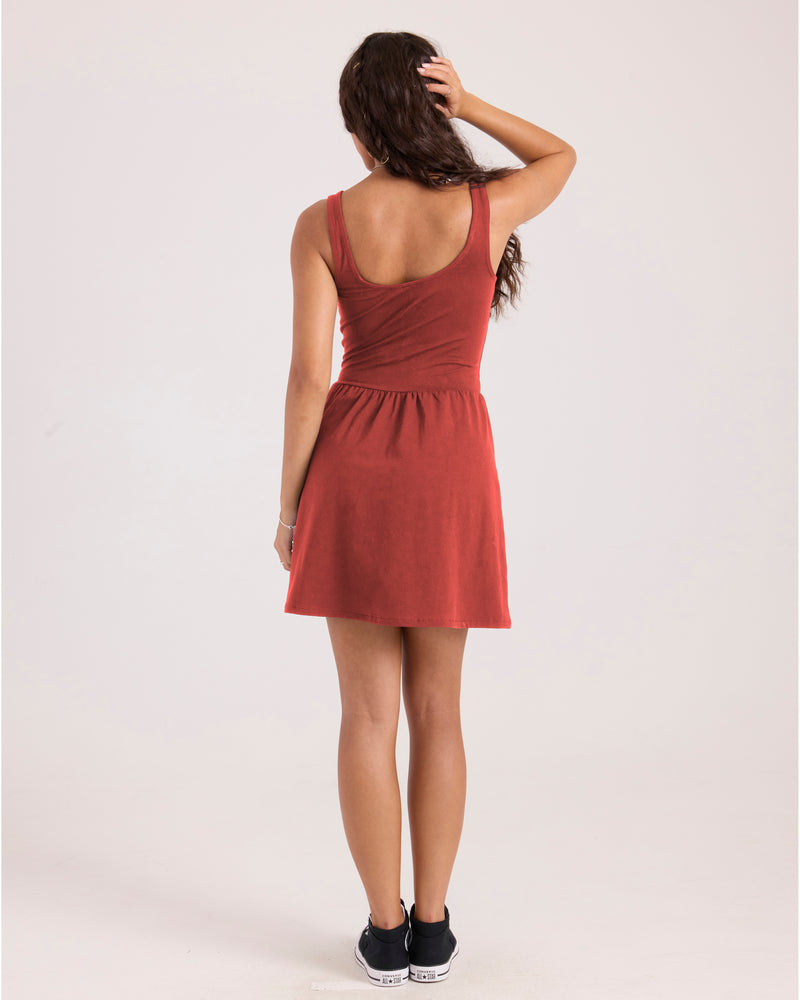 Back view of a person wearing a rust-colored knit Volcom Women’s Carve A-line mini dress and black high-top sneakers.