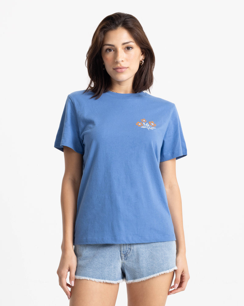 A person wears a blue, boxy-fit crew-neck Volcom Women’s Fleur De Stone Lock It Up Tee featuring a small floral graphic on the left chest.