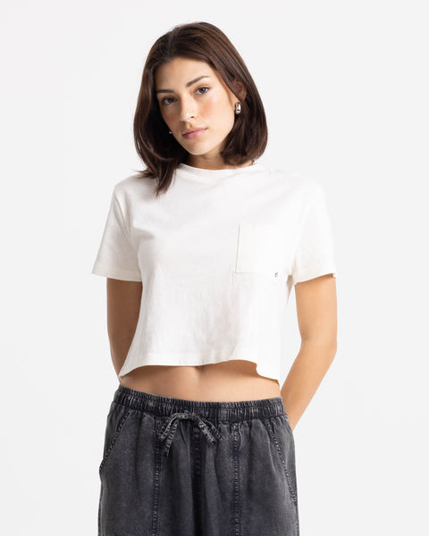 Woman with shoulder-length brown hair wears the Volcom Women’s BuTeeTeeerfly Ring Pocket Dial Tee and dark drawstring pants, standing against a plain white background.