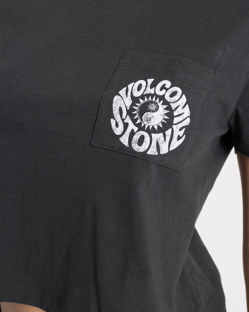 A close-up of a black Women’s Ying Yang Pocket Dial Tee by Volcom, featuring a boxy fit and a pocket with a white VOLCOM STONE sun and eye graphic logo at the center.