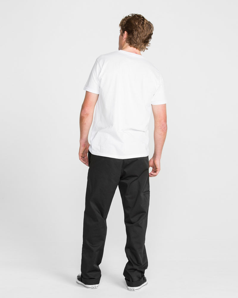 A person with short, light brown hair faces away from the camera, wearing a plain white t-shirt and Men's Frickin Relaxed Chino Pants with black-and-white sneakers against a plain white background.
