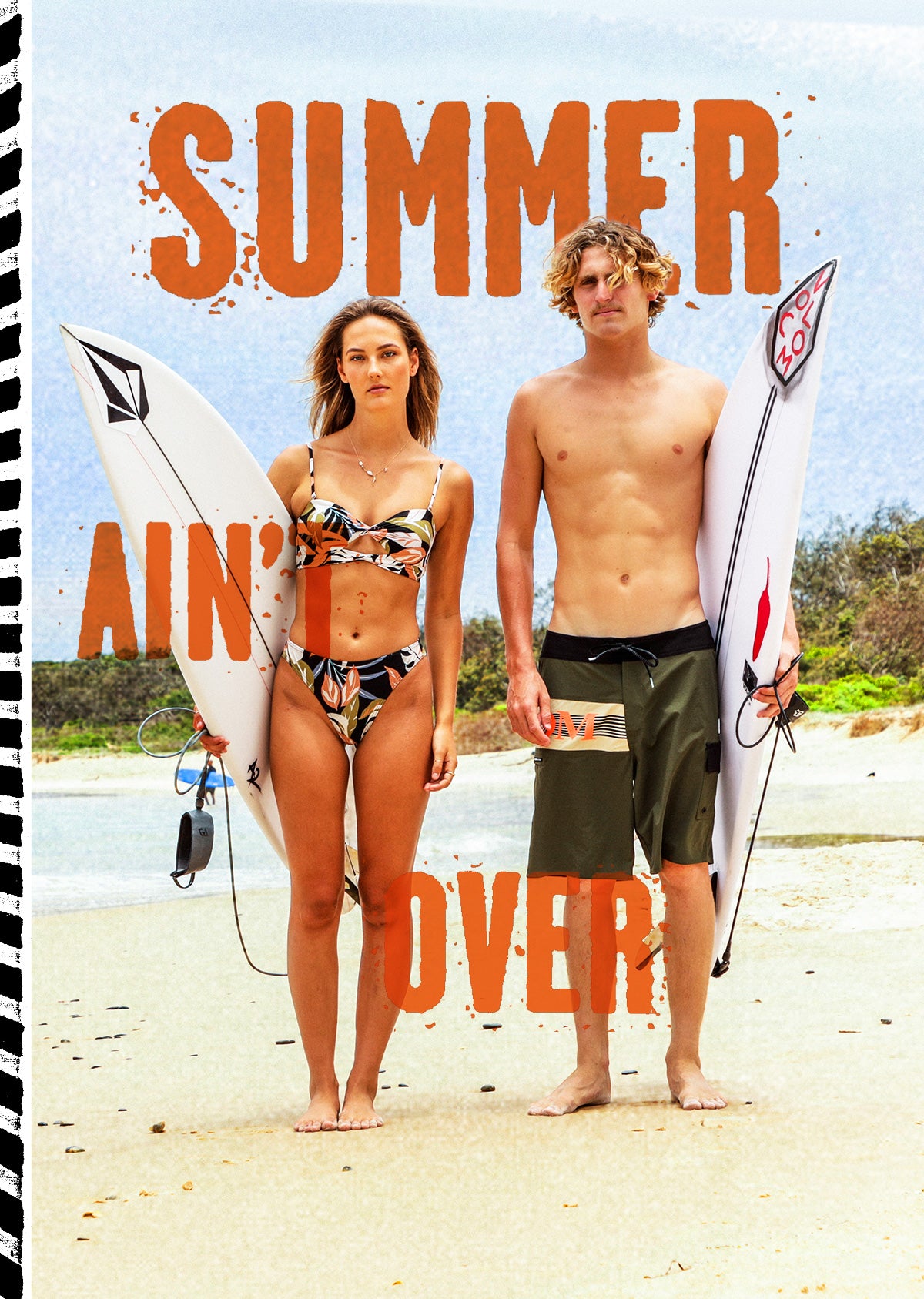 A beach scene with two people standing on sand holding surfboards, overlaid with large orange text reading 'SUMMER AIN'T OVER'. The woman wears a patterned bikini, and the man wears dark swim trunks.