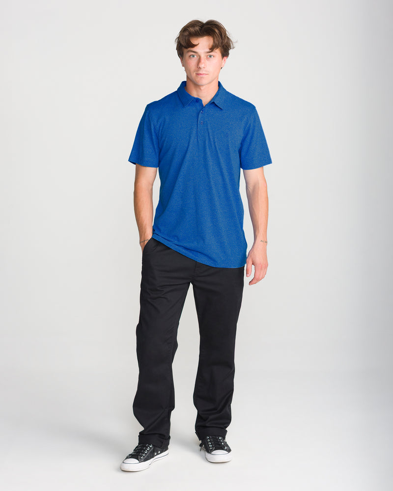 A person wearing a Men’s Wowzer Polo Short Sleeve in Nebulas Blue, black trousers, and black low-top sneakers.