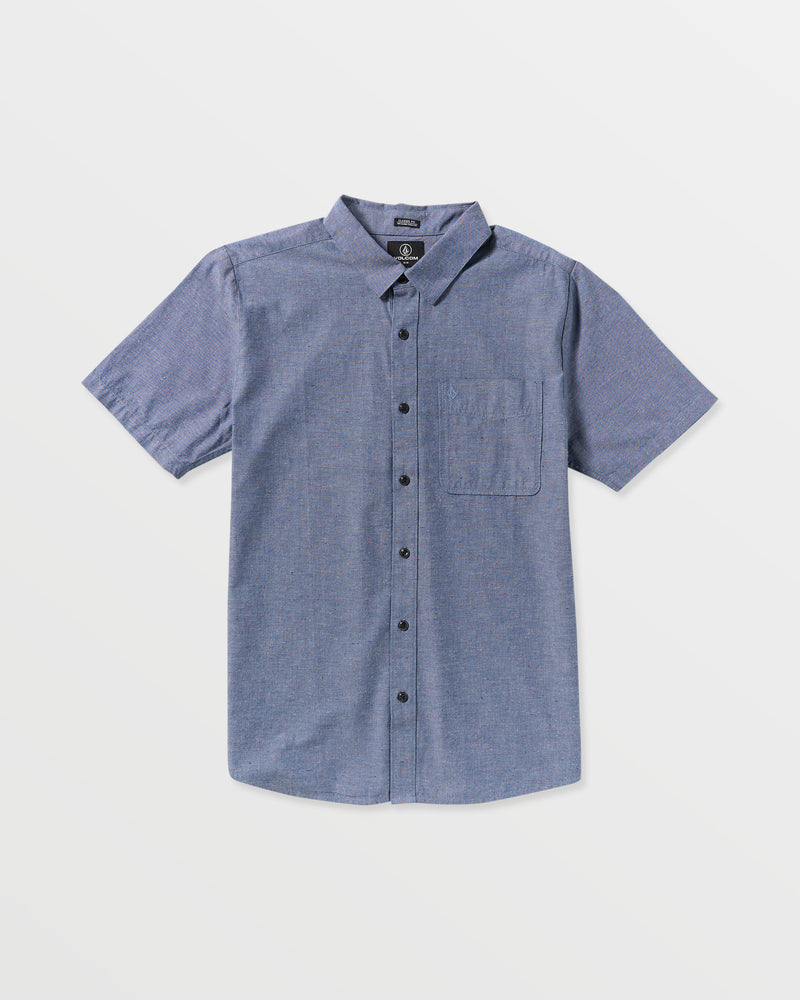 The Men's Date Knight Short Sleeve Shirt is a classic-fit, light blue button-up by Volcom, made from a premium cotton blend with a collar and single chest pocket, shown laid flat on a white background.