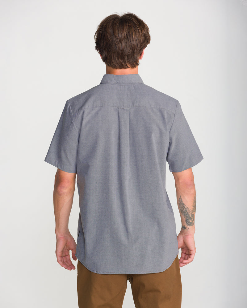 Back view of a person wearing a gray Men’s Everett Oxford II button-up shirt and brown pants.