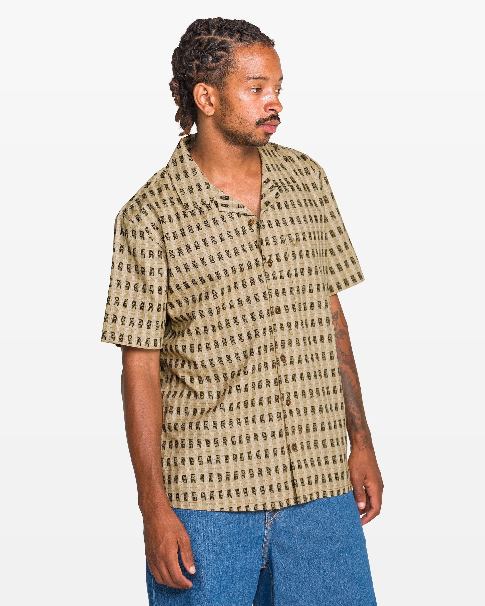 Man wearing a patterned shirt and blue jeans on a white background