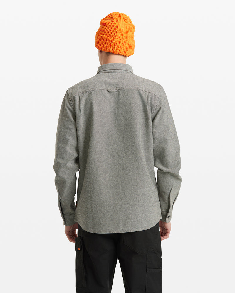 A person facing away shows the back of their outfit—wearing a bright orange knit beanie, black pants, and the Men's Levelstone Long Sleeve Shirt in light gray—against a plain white background.