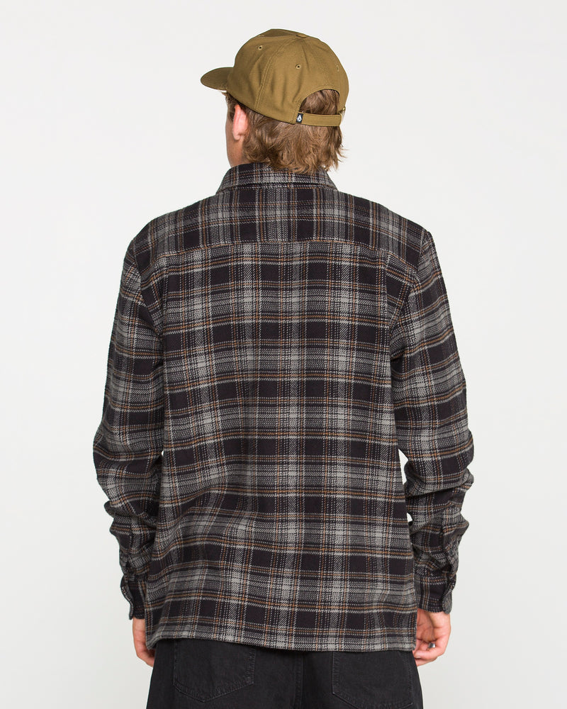 A person wearing a brown cap and a dark Volcom Men's Johnstone Long Sleeve Shirt is facing away from the camera against a plain white background.