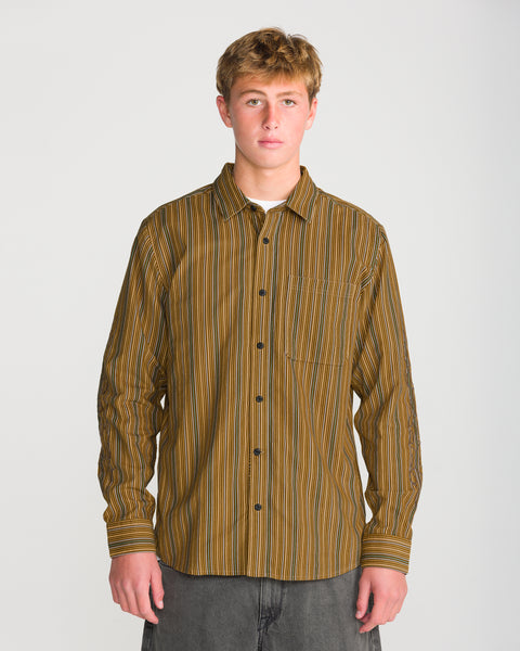 Brooklyn illustrator Casey Jones wears the Volcom Men’s Featured Artist Casey Jones Long Sleeve, a button-down shirt with vertical brown, yellow, and white stripes.