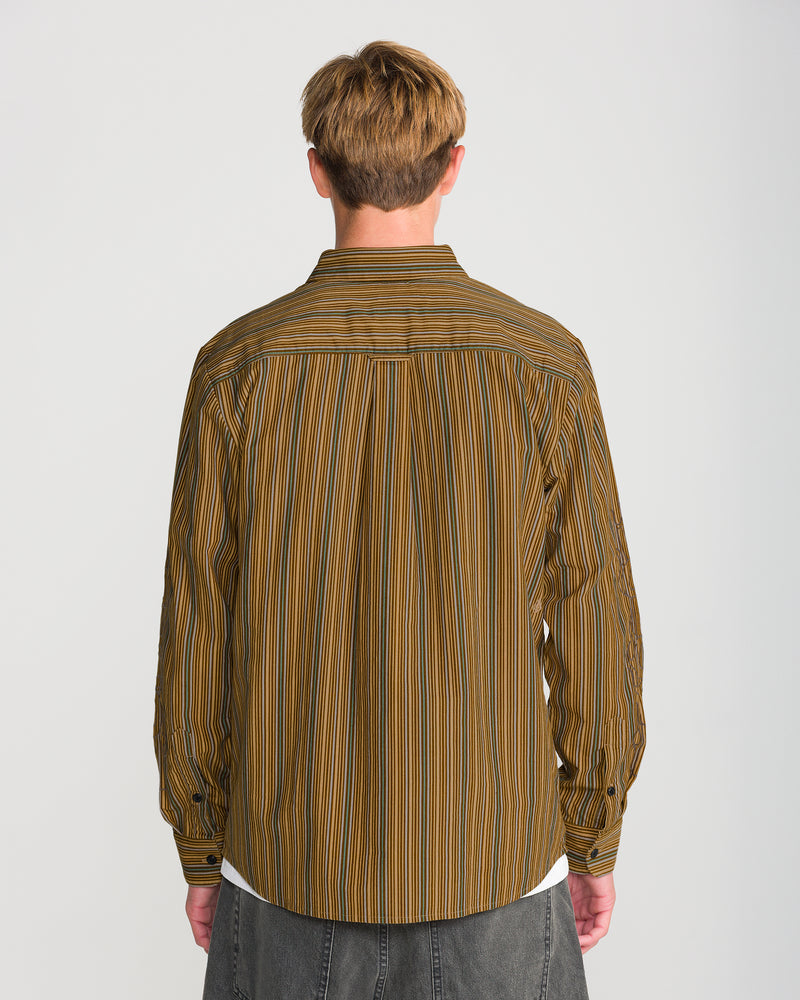 A person seen from behind wearing a Volcom Men’s Featured Artist Casey Jones Long Sleeve, a corduroy shirt with brown, green, and white vertical stripes.