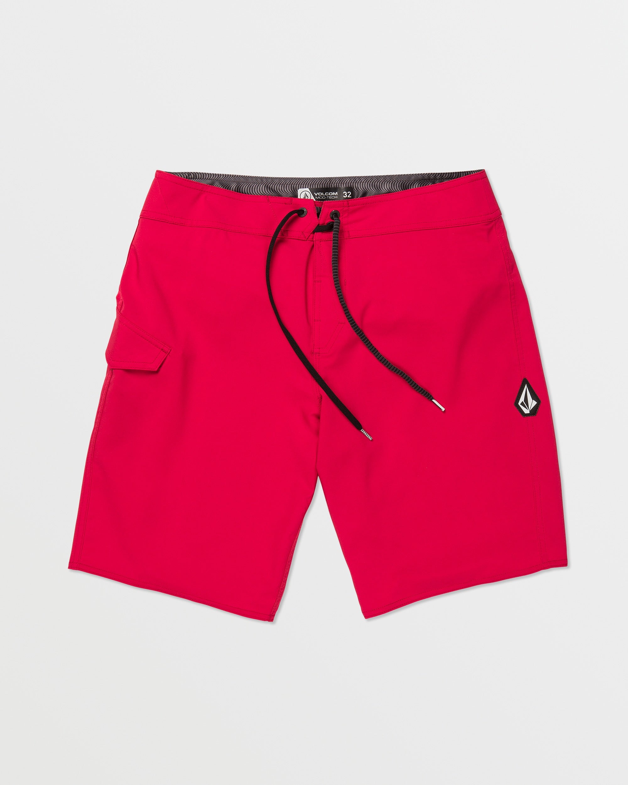 The Volcom Men's Lido Solid 20" Trunk features bright red 4-way stretch fabric, a black waistband and drawstring, a left side pocket, and a small black and white brand logo patch on the lower right leg, shown on a plain white background.