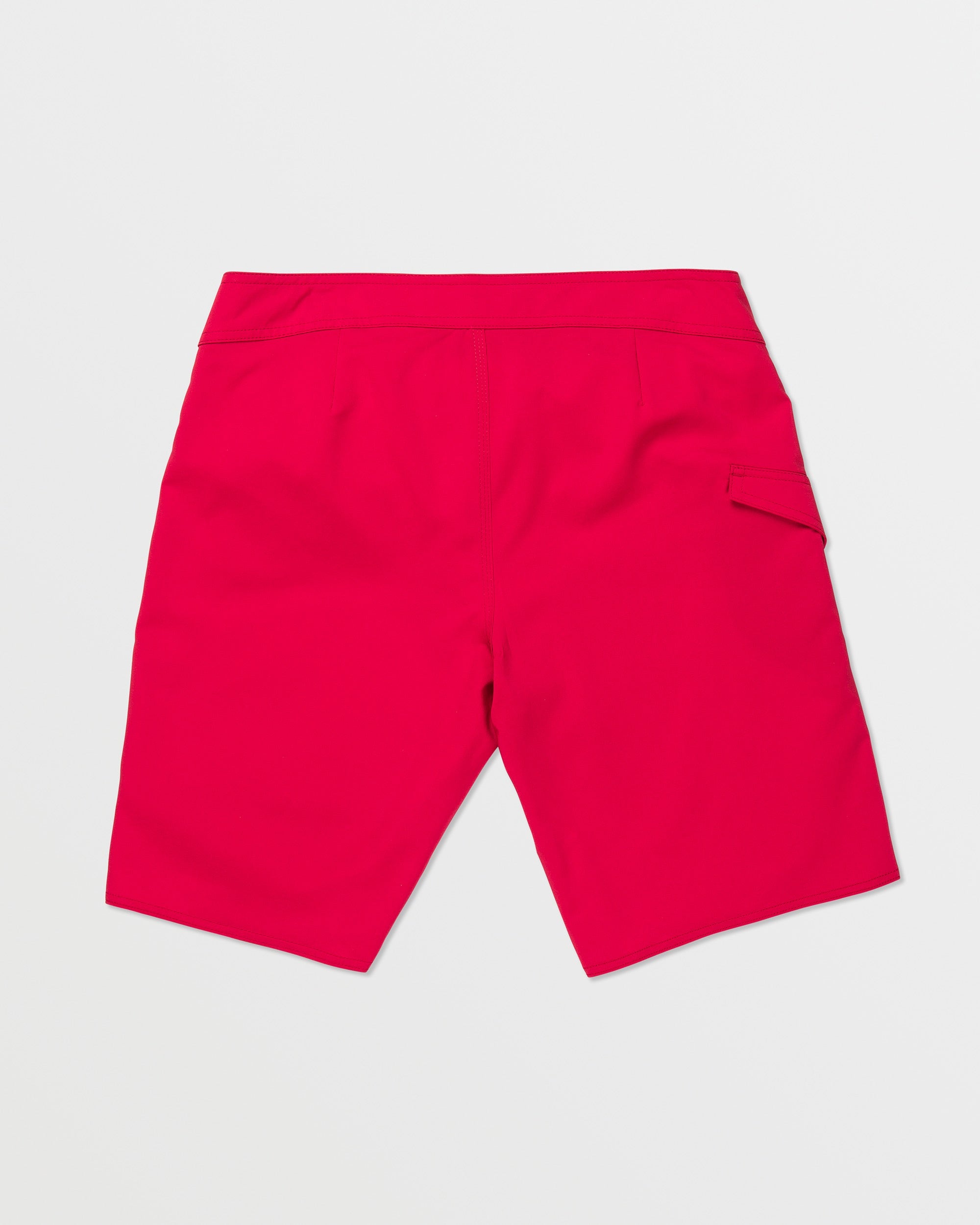 The Volcom Men's Lido Solid 20" Trunk is shown from the back in bright pink, featuring a right flap pocket and made with 4-way stretch recycled fibers, set against a plain white background.