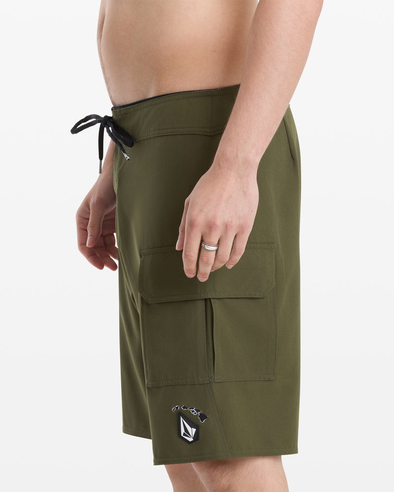 A man models the Volcom Men's Hawaii Truly Preemo Mod 20 olive green cargo swim trunks with a black drawstring, side pocket, and logo patch near the hem, shown from the side on a white background.