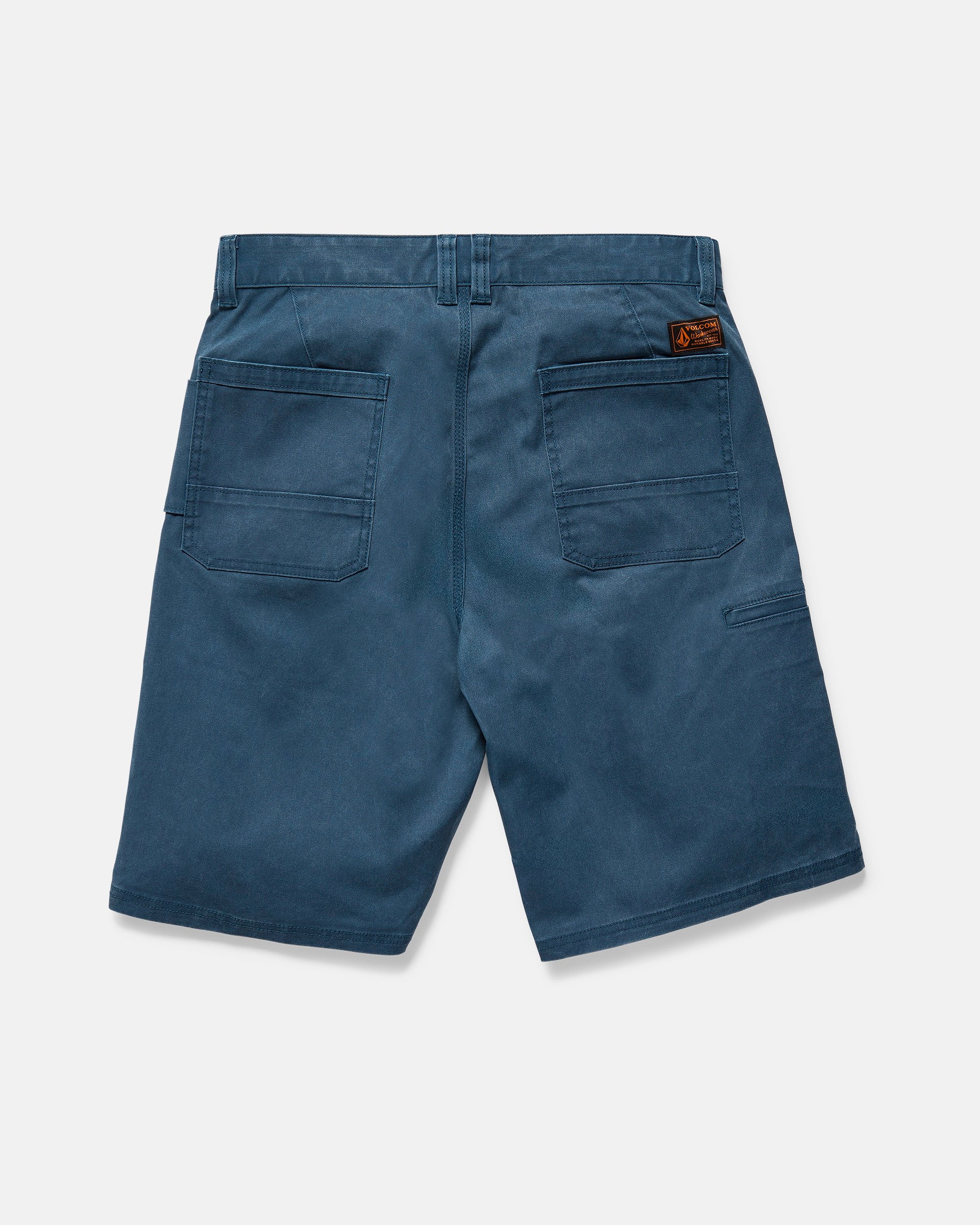 The Volcom Men's Dialed Relaxed Work Shorts in blue feature two large back pockets, a right-side smaller pocket, a brown logo patch above the right pocket, straight fit, belt loops, and durable utility style shown from the back.