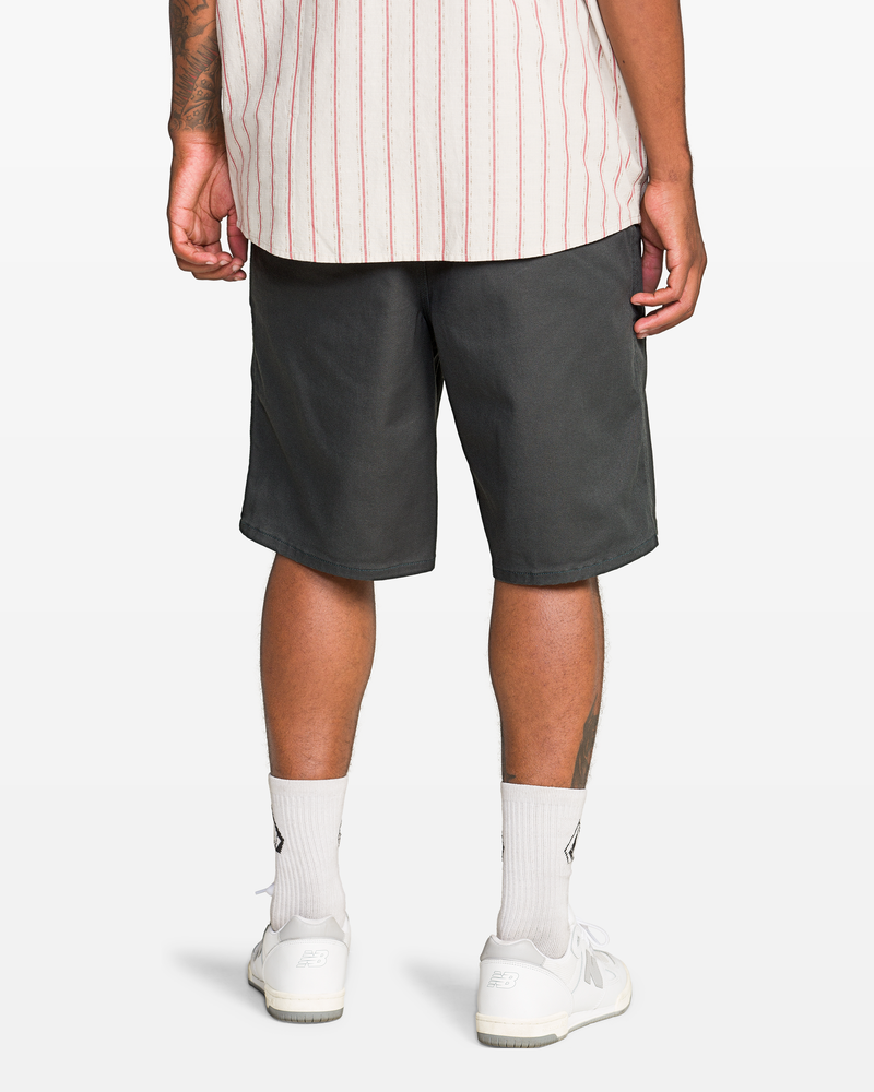 A person, shown from the waist down, wears the Volcom Men's Billow Short 22 with a striped shirt, white socks, and white sneakers.
