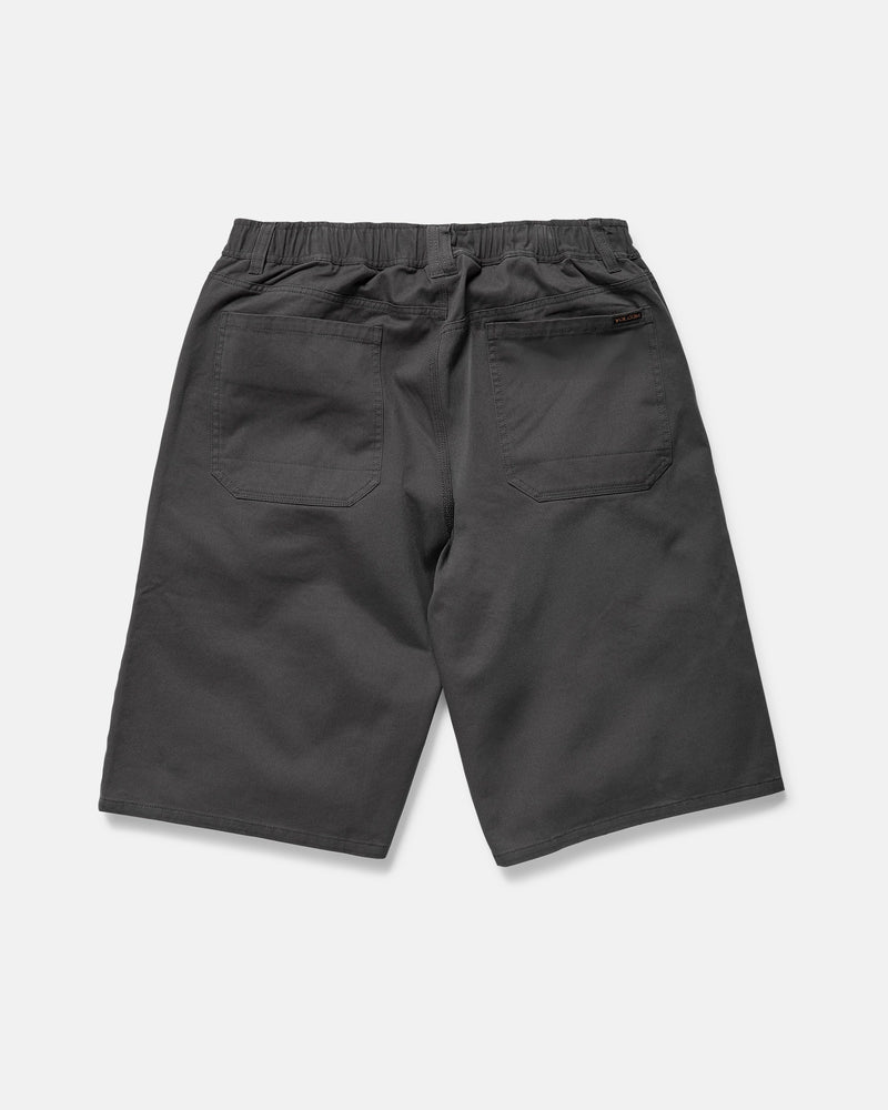 Back view of Volcom Men's Chillow Plt Elastic Waist Chino 24" Shorts Vs in dark gray cotton twill, featuring a baggy fit, elastic waistband, and two large back pockets, displayed on a white background.